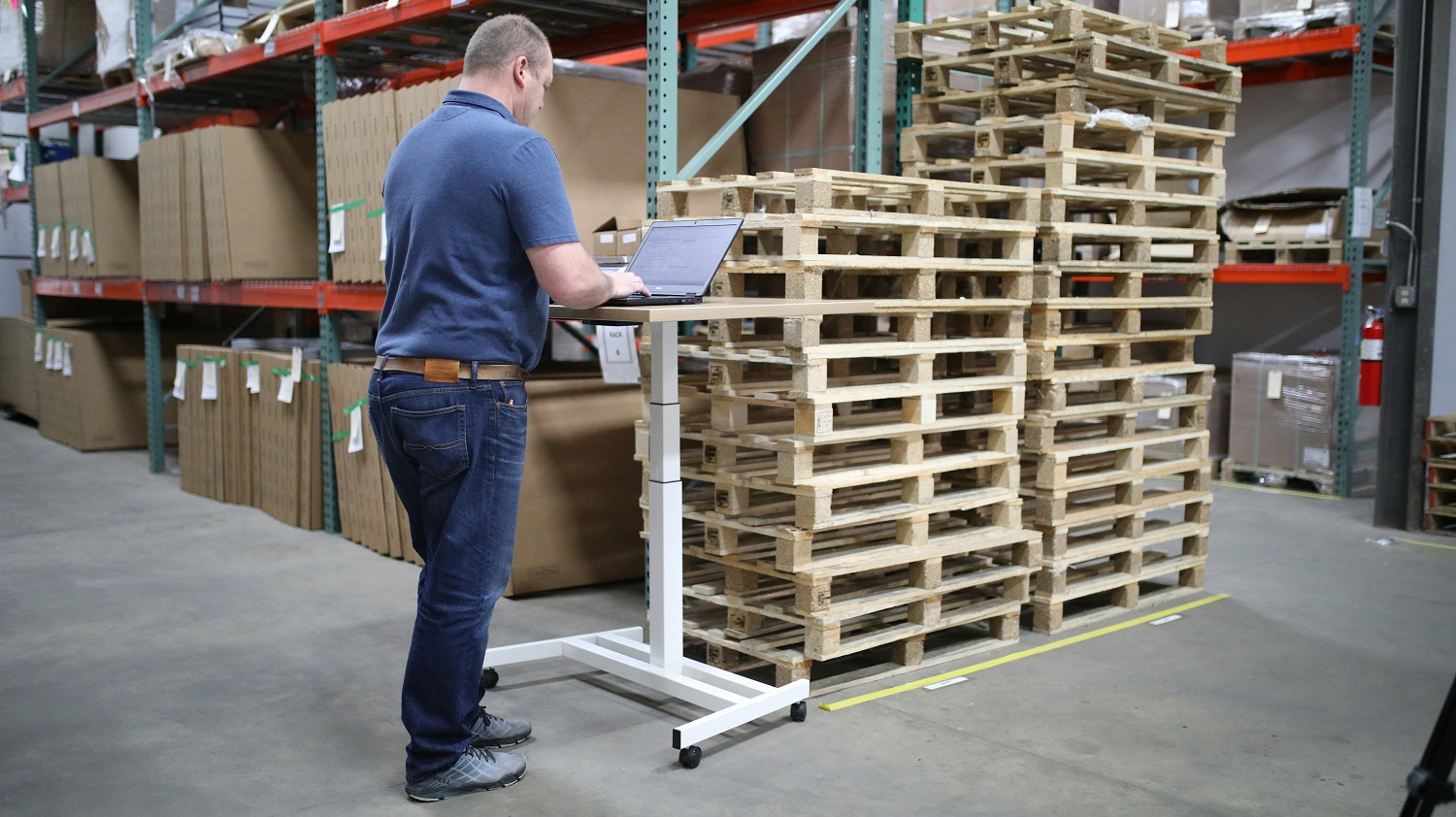Ein Mann steht vor einem Stapel Euro-Platten an einem Laptop