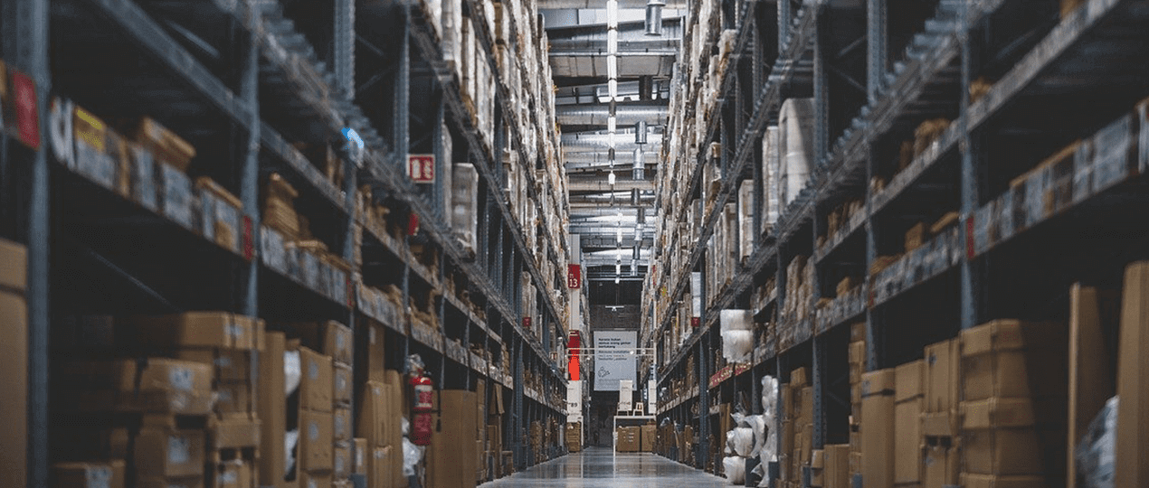 Blick in einen Gang einer Lagerhalle mit Hochregalen in denen jede Menge Pakete lagern. Wer Waren- und Informationsfluss synchronisiert, kommt dem optimalen Warenfluss sehr nahe!