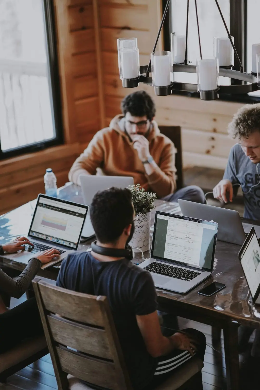 Team sitzt gemeinsam am Tisch mit Laptops und plant Vertriebsstrategie.