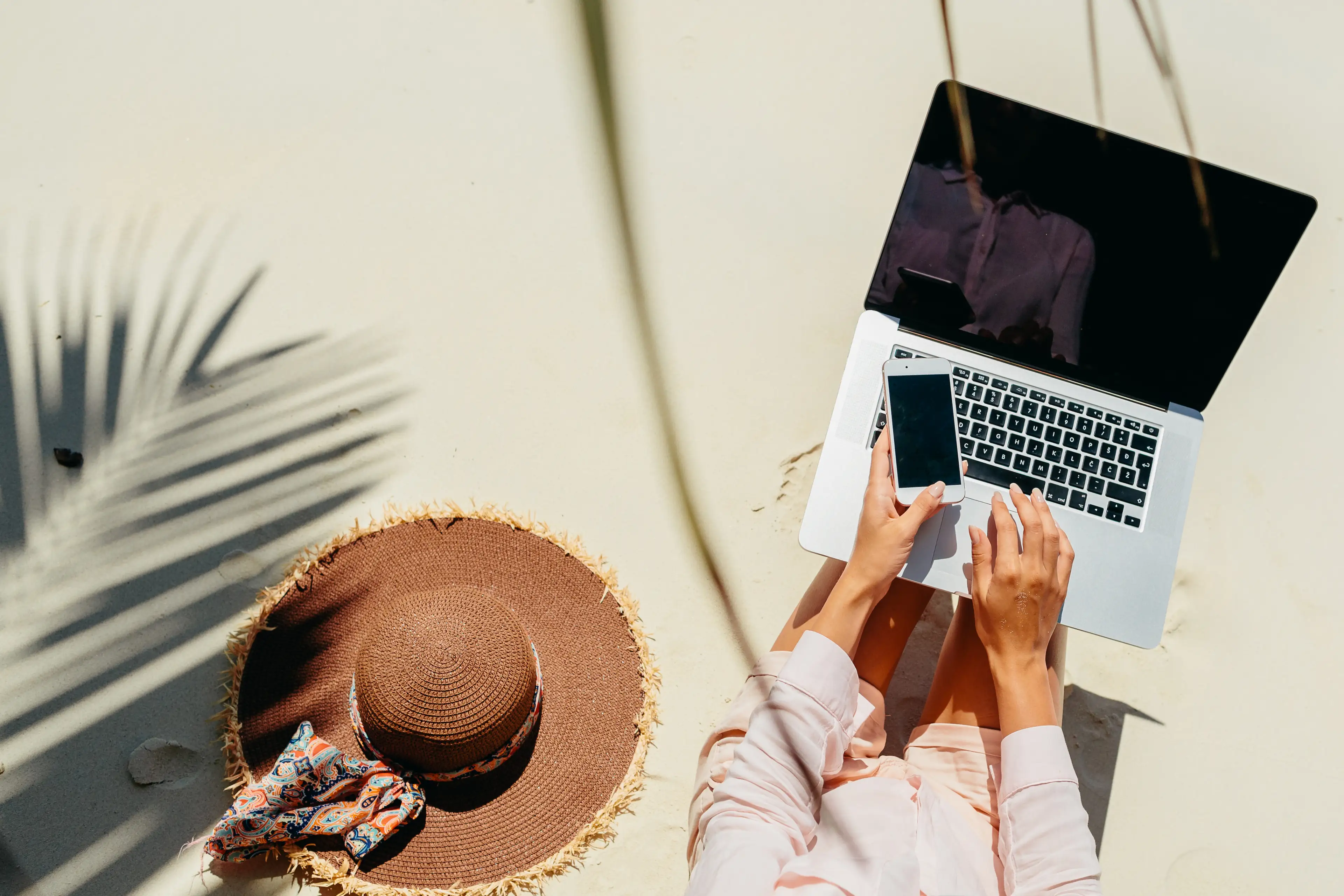 Person arbeitet draußen am Laptop mit Hut, Symbol für den internationalen Markt.